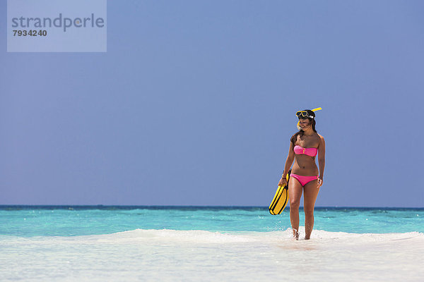 Junge Frau  etwa 20 Jahre  geht auf einer Sandbank  mit Schnorchelausrüstung