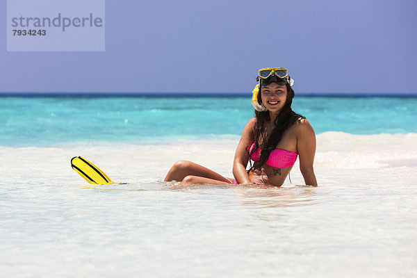 Junge Frau  etwa 20 Jahre  sitzt auf einer Sandbank  mit Schnorchelausrüstung
