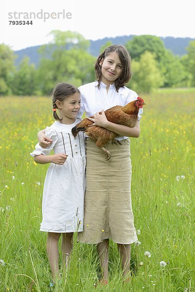 Zwei Schwestern mit einem Huhn