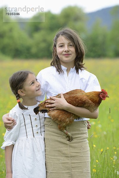 Zwei Schwestern mit einem Huhn