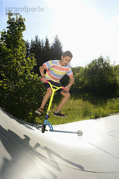 Junge mit Kickboard in einem Skatepark