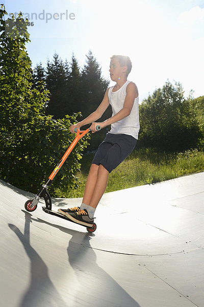 Junge mit Kickboard in einem Skatepark