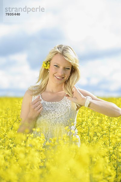 Blonde junge Frau in blühendem Rapsfeld