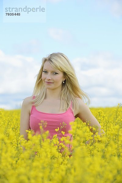 Blonde junge Frau in blühendem Rapsfeld