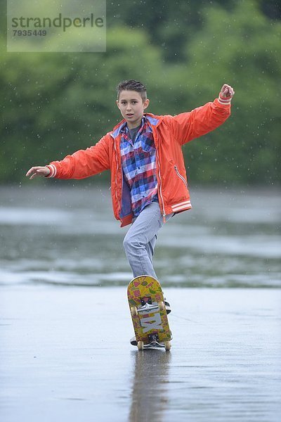 Junge mit Skateboard an einem regnerischen Tag