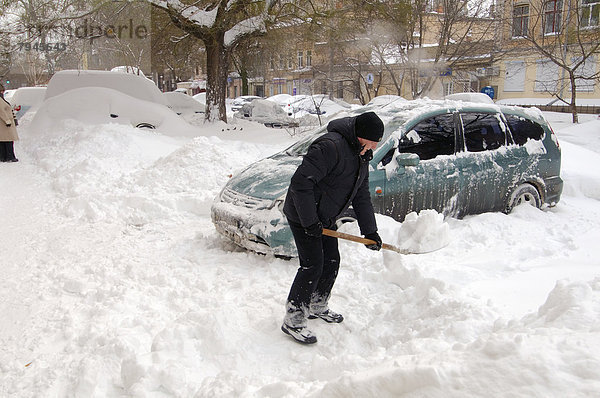 Mann entfernt Schnee von seinem Auto