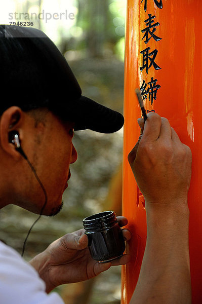 Mann schreibt Namen von Spendern mit einem Pinsel auf ein Torii  Shint?-Schrein Fushimi Inari-Taisha