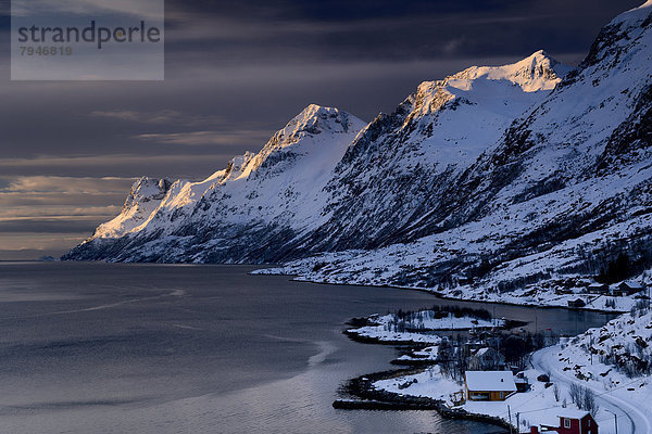 Fjord mit kleiner Ortschaft im Abendlicht