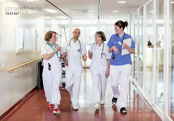 Ärzteteam kommuniziert beim Gehen im Krankenhausflur