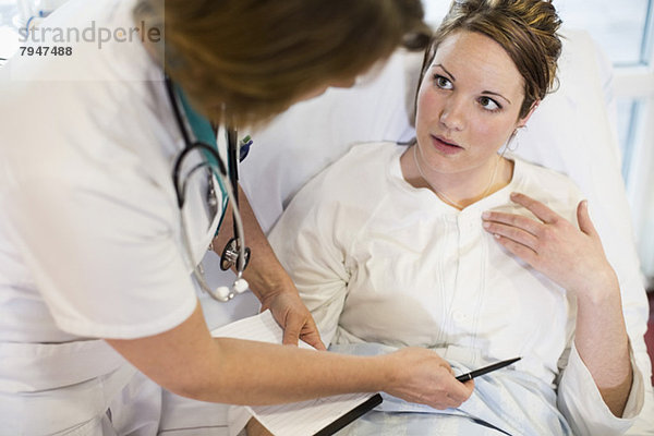 Hochwinkelansicht der Patientin in der Kommunikation mit dem Arzt auf der Krankenstation