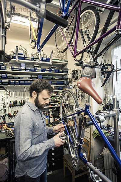 Mittlerer Erwachsener  der in der Fahrradwerkstatt arbeitet.