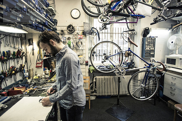 Profilaufnahme eines mittleren Erwachsenen  der in einer Fahrradwerkstatt arbeitet.