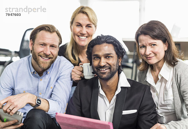 Porträt glücklicher multiethnischer Geschäftsleute  die zusammen im Büro sitzen