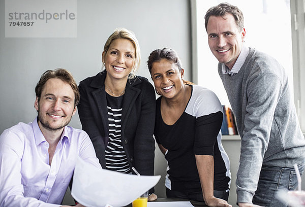 Portrait von glücklichen Geschäftskollegen am Schreibtisch im Büro