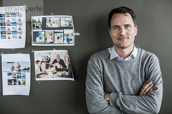 Porträt eines Geschäftsmannes  der im Büro an der Wand steht.