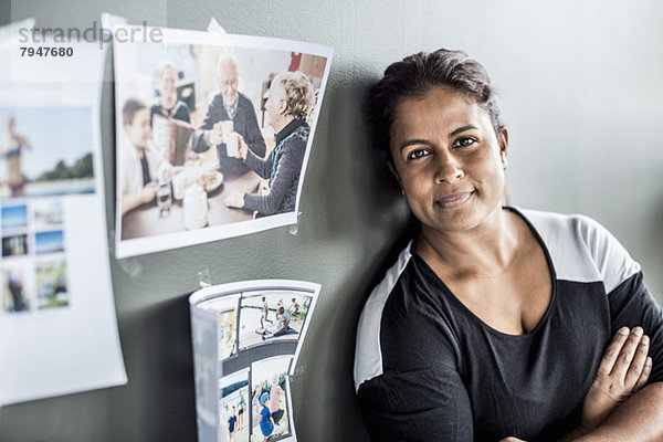 Porträt einer Geschäftsfrau mit gekreuzten Armen an der Wand im Büro