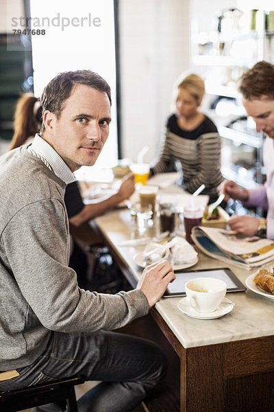 Porträt eines mittelständischen Geschäftsmannes mit Kollegen beim Frühstück im Bürorestaurant
