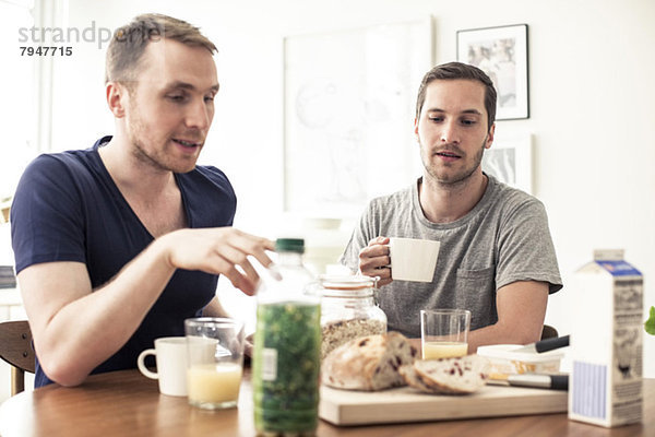 Homosexuelles Paar beim gemeinsamen Frühstück am Tisch zu Hause