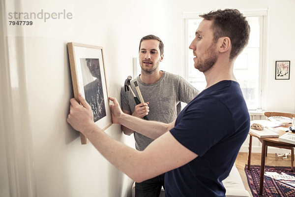 Homosexuelles Paar hängender Bilderrahmen an der Wand zu Hause