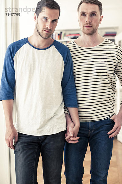Porträt eines homosexuellen Paares  das zu Hause Händchen hält
