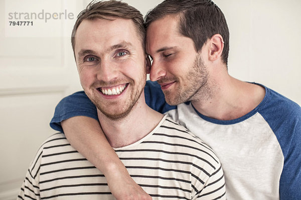 Porträt eines glücklichen jungen schwulen Mannes mit einem romantischen Partner zu Hause.