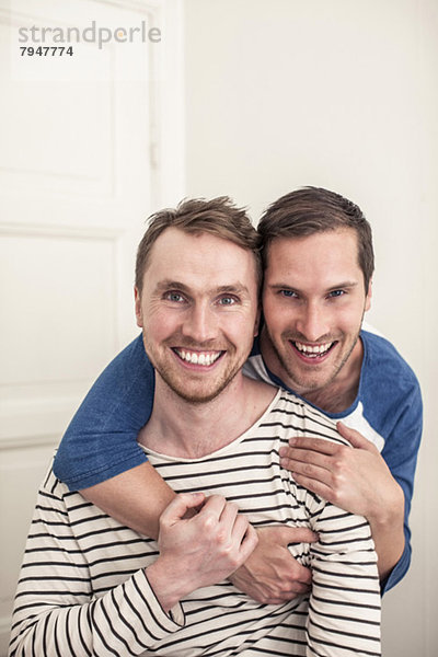 Portrait glücklicher schwuler Mann  der den Partner von hinten umarmt.