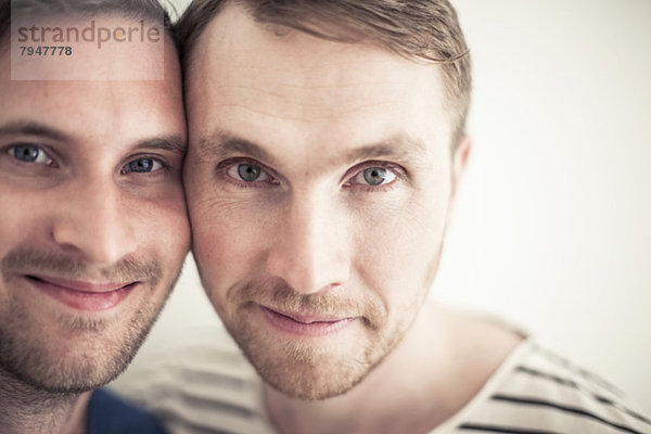 Porträt eines jungen homosexuellen Paares  das Wange an Wange lächelt.
