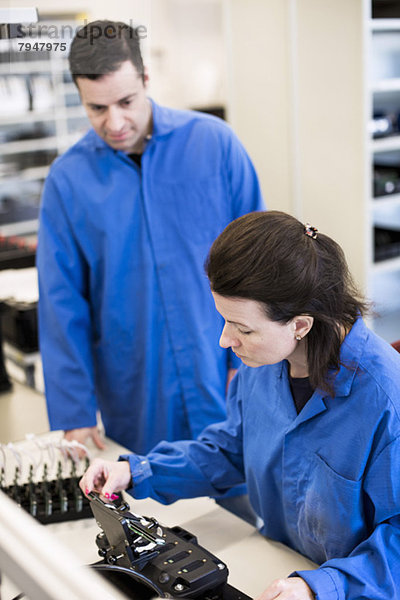 Eine Technikerin  die die Maschine analysiert  während eine Kollegin sie in der Industrie ansieht.