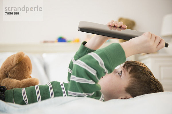 liegend  liegen  liegt  liegendes  liegender  liegende  daliegen  Junge - Person  halten  Bett  Tablet PC  5-6 Jahre  5 bis 6 Jahre