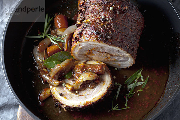 Rolled roast pork and braised vegetables in frying pan  close up