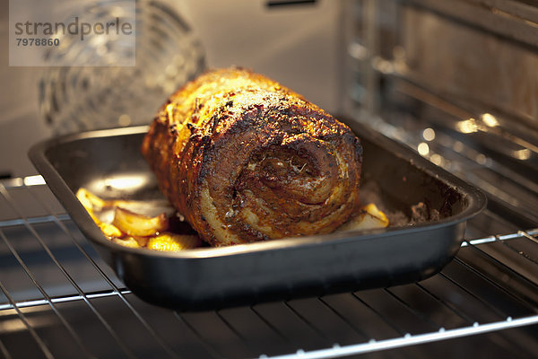 Gerolltes gebratenes Schweinefleisch auf Blech im Ofen  Nahaufnahme