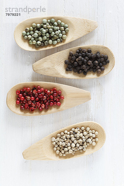 Variety of peppercorns on wooden spoon  close up