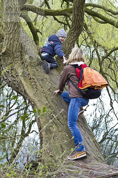 Deutschland  Kiel  Mutter und Sohn klettern am Baum