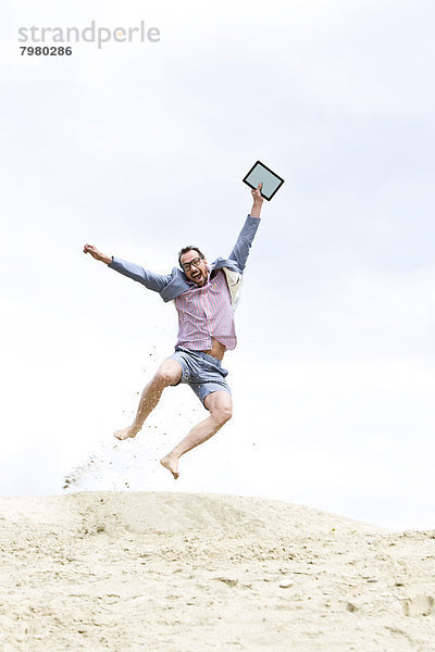 Erwachsener Mann springt mit digitalem Tablett