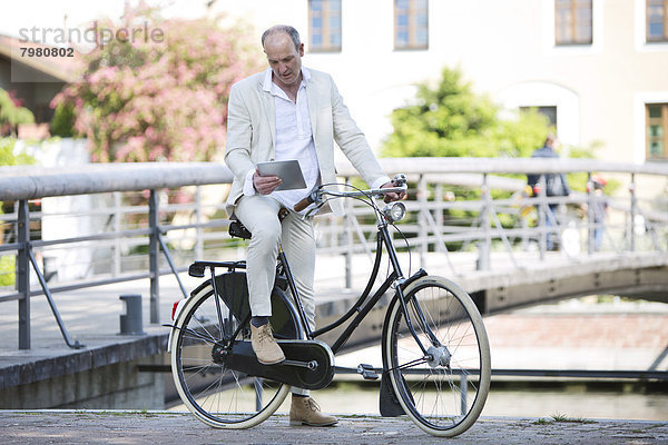 Erwachsener Mann mit Fahrrad und digitalem Tablett