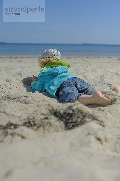 Deutschland  Mecklenburg-Vorpommern  Junge entspannt auf Sand an der Ostsee