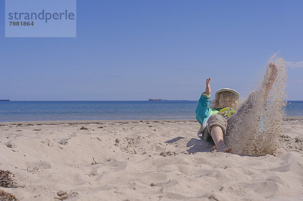 Deutschland  Mecklenburg-Vorpommern  Junge spielt mit Sand an der Ostsee