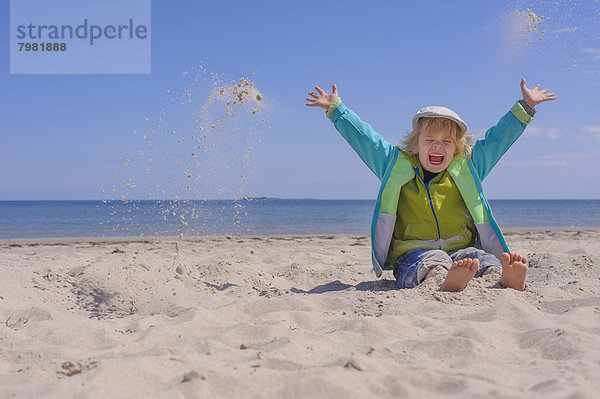 Deutschland  Mecklenburg-Vorpommern  Junge spielt mit Sand an der Ostsee
