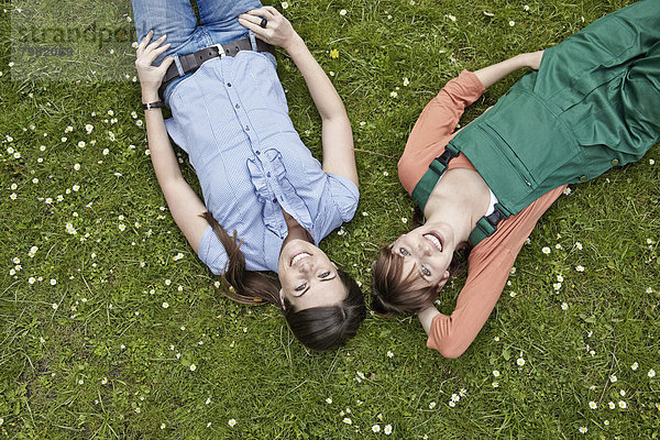 Junge Frauen auf Gras liegend  lächelnd