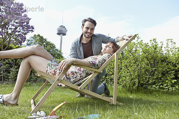 Deutschland  Köln  Junges Paar entspannt im Garten  lächelnd