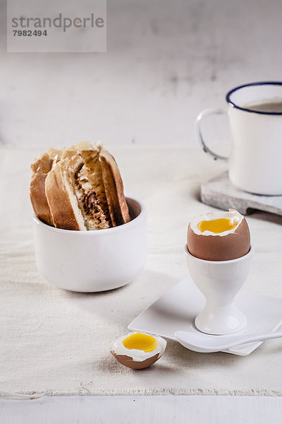 Ei im Eierbecher mit geröstetem Weißbrot und Kaffeetasse  Nahaufnahme