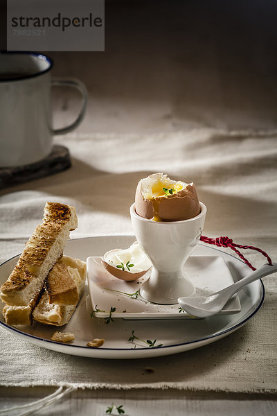 Ei mit geröstetem Weißbrot auf Teller und Kaffeetasse  Nahaufnahme