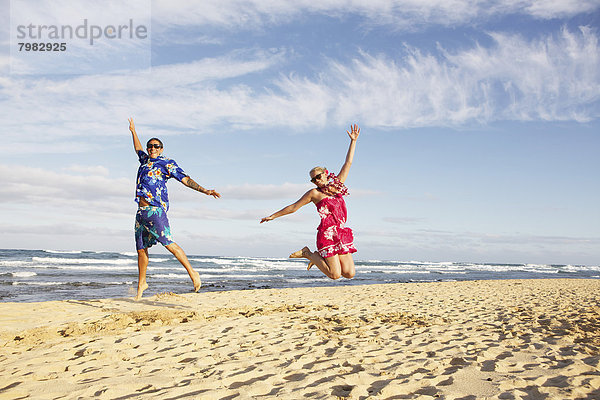 USA  Hawaii  Mittleres erwachsenes Paar beim Springen am Strand