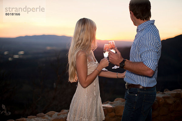 Junges Paar bei Sonnenuntergang im Freien mit Champagner