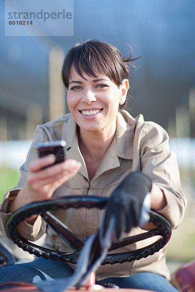 Frau im Fahrzeug mit Handy in der Gärtnerei