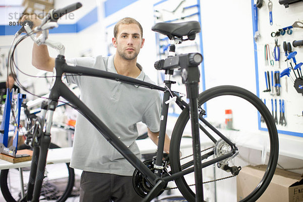 Junger Mann in der Werkstatt mit Fahrrad