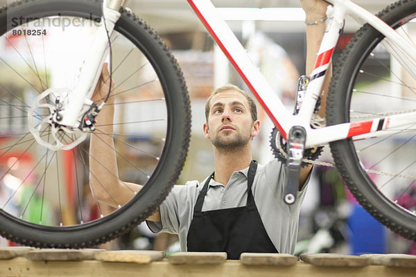 Junger Mann mit Fahrrad in der Werkstatt