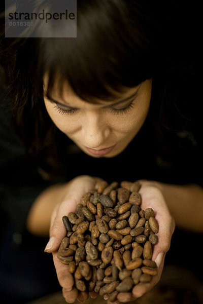 Eine Frau hält eine Handvoll Kakaobohnen.