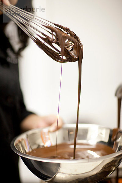 Frau mit Rührschüssel und geschmolzener Schokolade