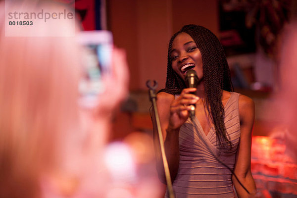 Junge Frau singt mit Mikrofon